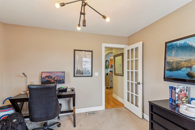 office area with arched walkways, french doors, light carpet, and baseboards