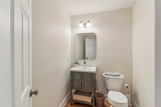 bathroom with toilet, baseboards, and vanity