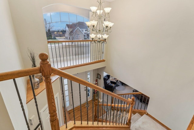 staircase with baseboards, a notable chandelier, and a high ceiling