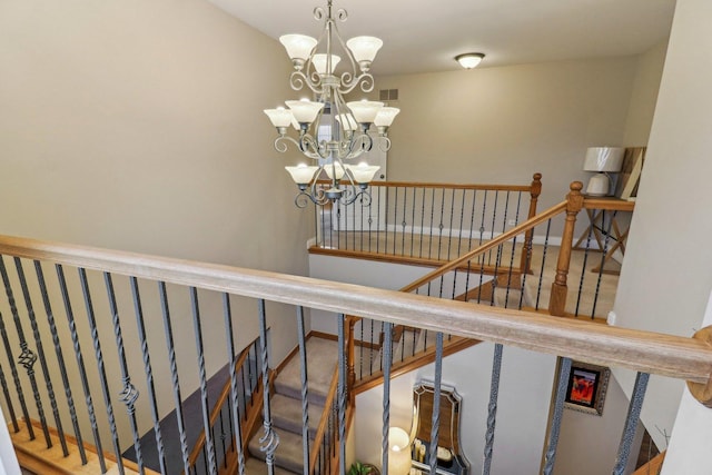 stairway with visible vents, a notable chandelier, and baseboards