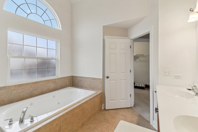 bathroom with tile patterned flooring, a sink, a bath, double vanity, and a walk in closet