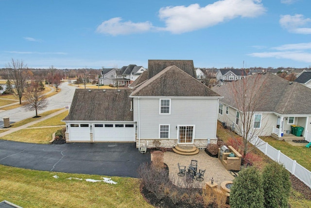 view of front of home with an attached garage, a residential view, fence, and a front yard