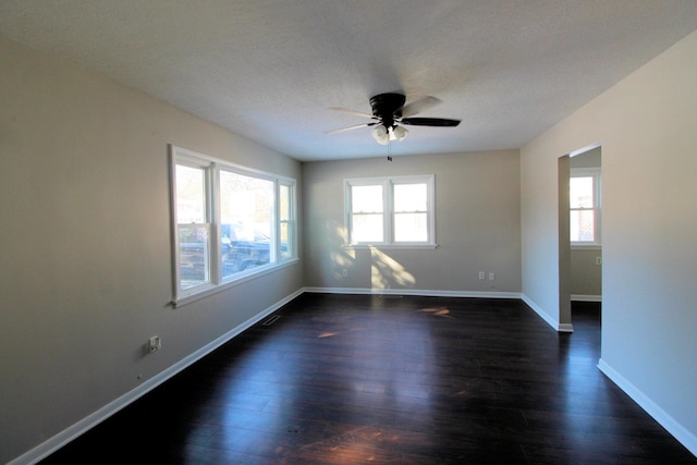 unfurnished room featuring dark wood-style flooring, ceiling fan, a textured ceiling, and baseboards