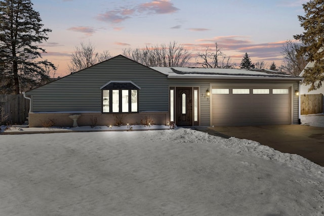 view of front of house with an attached garage, driveway, and fence