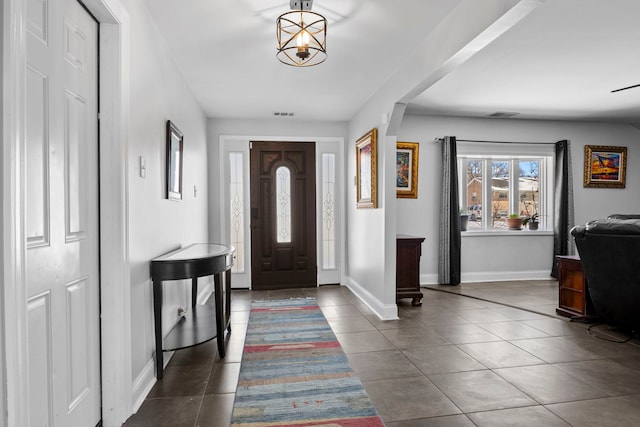 entryway with dark tile patterned flooring, visible vents, and baseboards