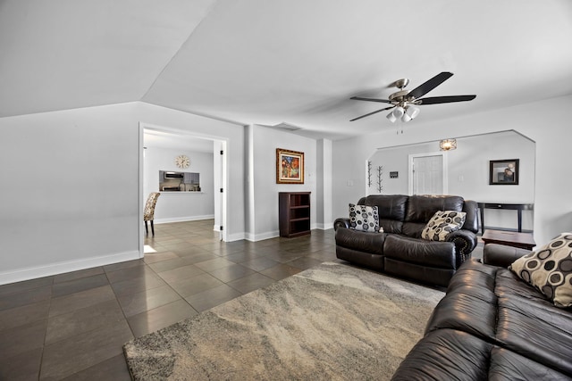 living area featuring ceiling fan, dark tile patterned floors, visible vents, baseboards, and vaulted ceiling