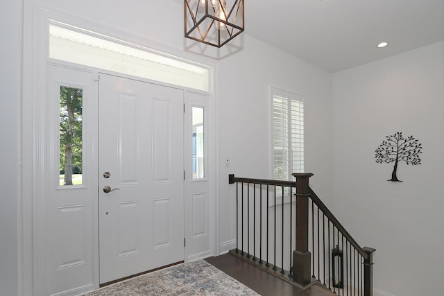 foyer entrance with a notable chandelier, dark wood-type flooring, and recessed lighting