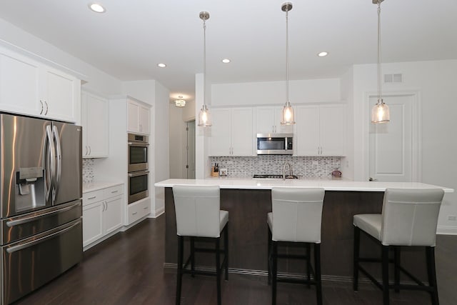 kitchen with pendant lighting, a center island with sink, light countertops, visible vents, and appliances with stainless steel finishes