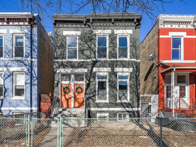 italianate-style house with entry steps and a fenced front yard