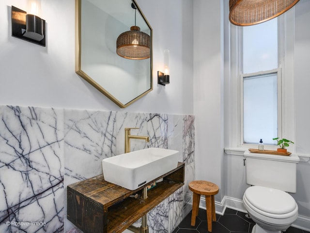 half bath featuring tile walls, a sink, toilet, and tile patterned floors