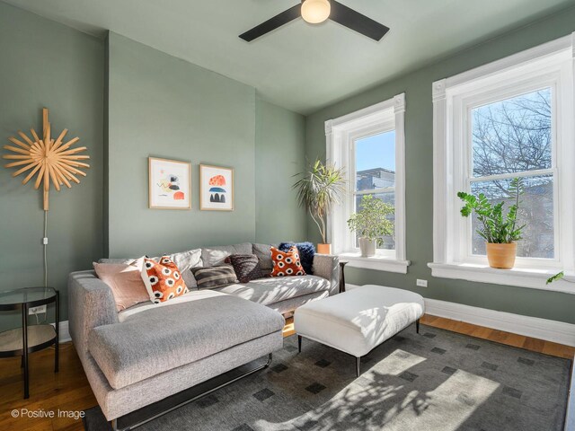 living room featuring a ceiling fan, baseboards, and wood finished floors