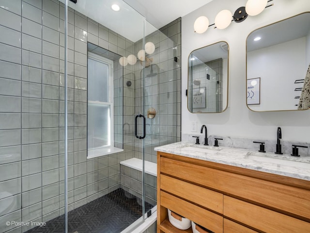 bathroom with a sink, a shower stall, and double vanity