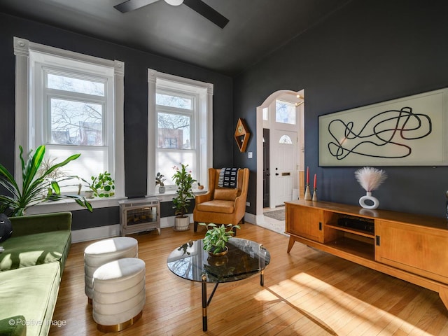 living room with arched walkways, ceiling fan, wood finished floors, and baseboards