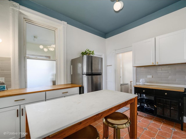 kitchen featuring light countertops, tasteful backsplash, freestanding refrigerator, and white cabinetry