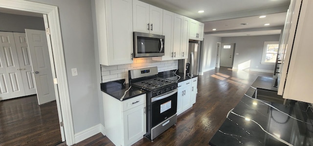 kitchen featuring baseboards, dark wood-style flooring, appliances with stainless steel finishes, dark countertops, and backsplash