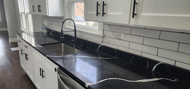 kitchen with decorative backsplash, stainless steel dishwasher, dark wood-style floors, white cabinetry, and a sink