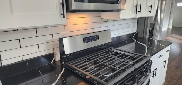 room details featuring dark countertops, white cabinets, stainless steel range with gas stovetop, and tasteful backsplash