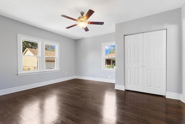 unfurnished bedroom with dark wood-style floors, ceiling fan, a closet, and baseboards