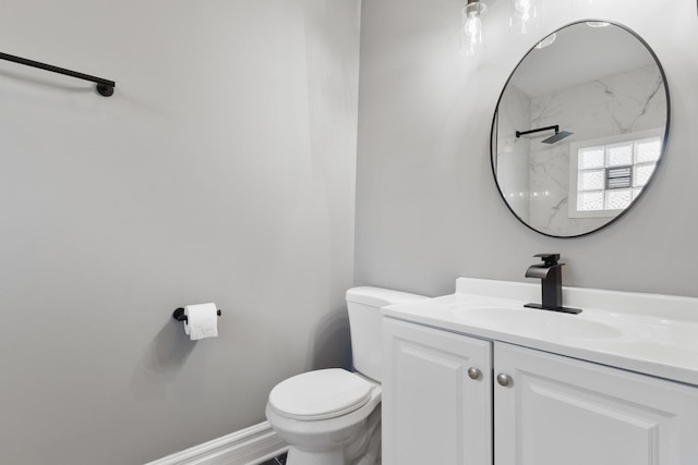 bathroom with toilet, vanity, and baseboards