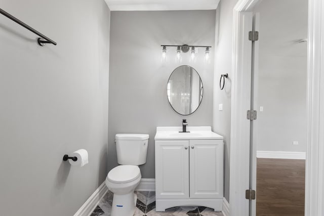 half bathroom featuring vanity, toilet, and baseboards