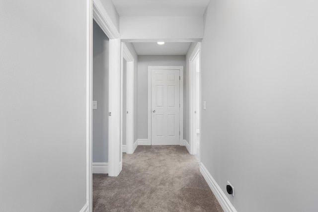 corridor featuring baseboards and carpet floors