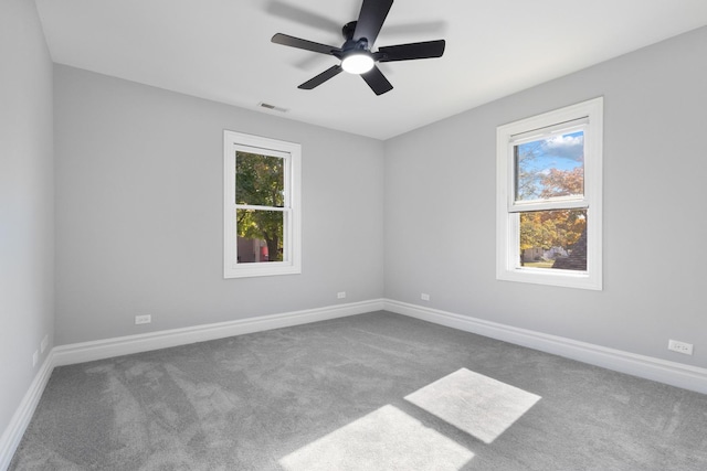 carpeted empty room with visible vents, a ceiling fan, and baseboards