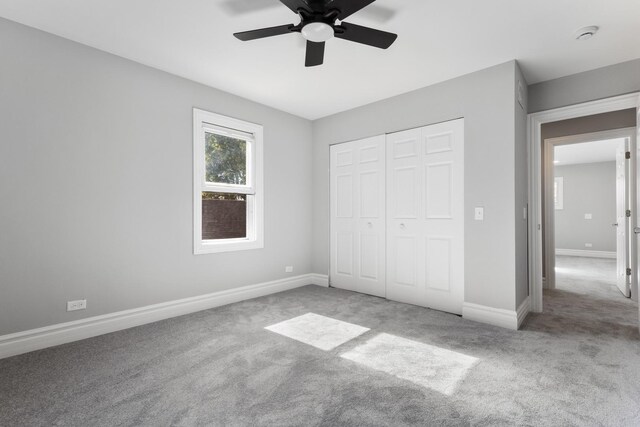 unfurnished bedroom with a closet, carpet flooring, a ceiling fan, and baseboards