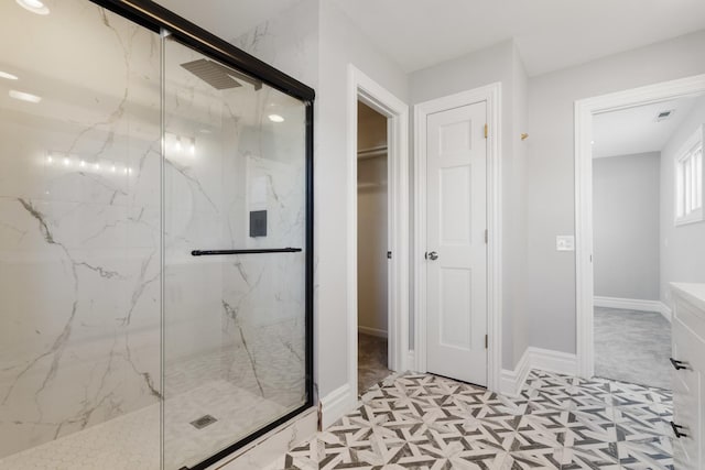 full bathroom with tile patterned floors, visible vents, a walk in closet, a marble finish shower, and baseboards