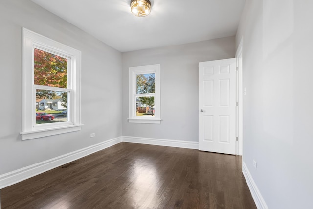 empty room featuring baseboards, plenty of natural light, visible vents, and dark wood finished floors