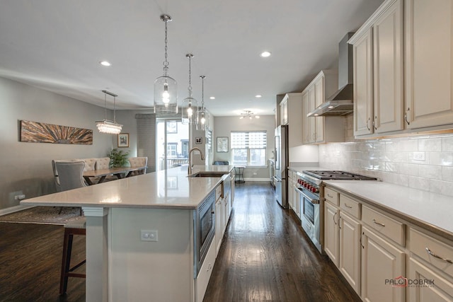 kitchen featuring a sink, premium appliances, a kitchen breakfast bar, tasteful backsplash, and wall chimney range hood