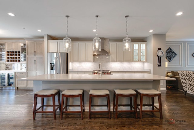 kitchen featuring wall chimney range hood, a spacious island, wine cooler, light countertops, and high end refrigerator