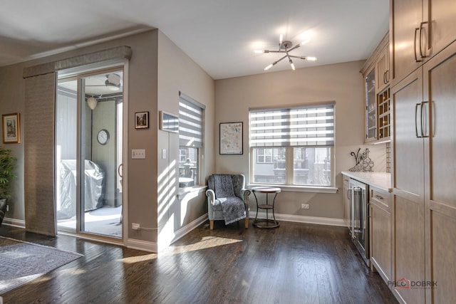 living area with baseboards, wine cooler, a notable chandelier, and dark wood-style flooring