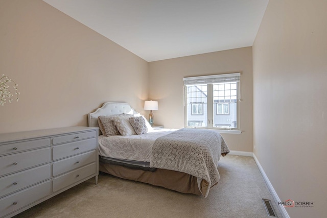 bedroom featuring visible vents, light colored carpet, and baseboards