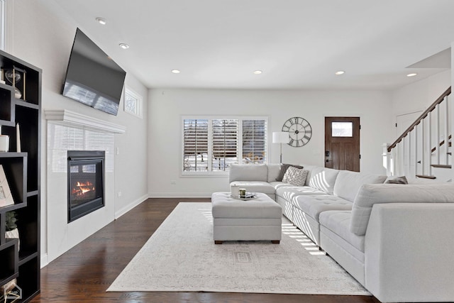 living room with baseboards, dark wood finished floors, a tiled fireplace, stairway, and recessed lighting