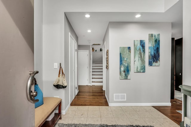 corridor with baseboards, visible vents, stairs, light tile patterned flooring, and recessed lighting