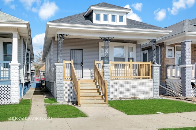 shotgun-style home with a porch and roof with shingles