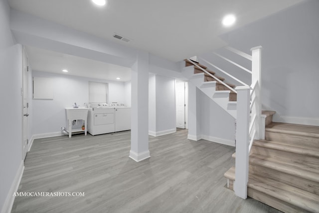 finished below grade area featuring light wood-style floors, stairs, visible vents, and independent washer and dryer