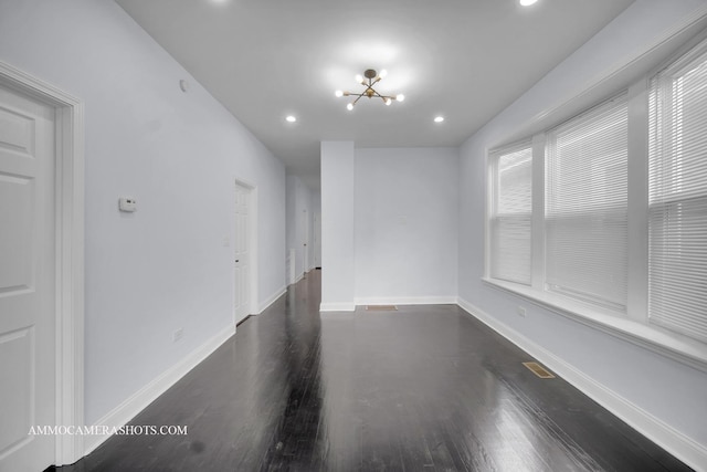 empty room with a notable chandelier, baseboards, dark wood-style flooring, and recessed lighting