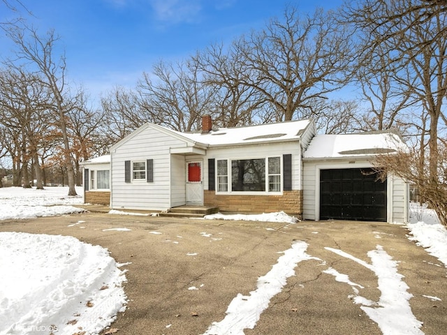 view of front of property featuring driveway, a chimney, and a garage