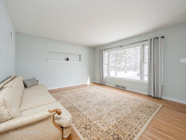 living room featuring visible vents, baseboards, and wood finished floors