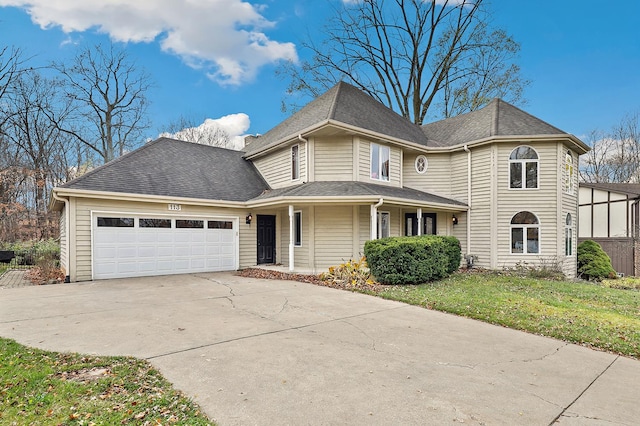 view of front of home featuring a garage, roof with shingles, concrete driveway, and a front yard