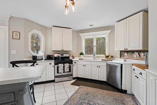 kitchen featuring light countertops, appliances with stainless steel finishes, light tile patterned flooring, and white cabinetry