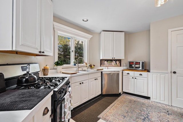 kitchen featuring white cabinets, stainless steel dishwasher, and gas range