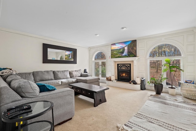 carpeted living room featuring a lit fireplace and ornamental molding