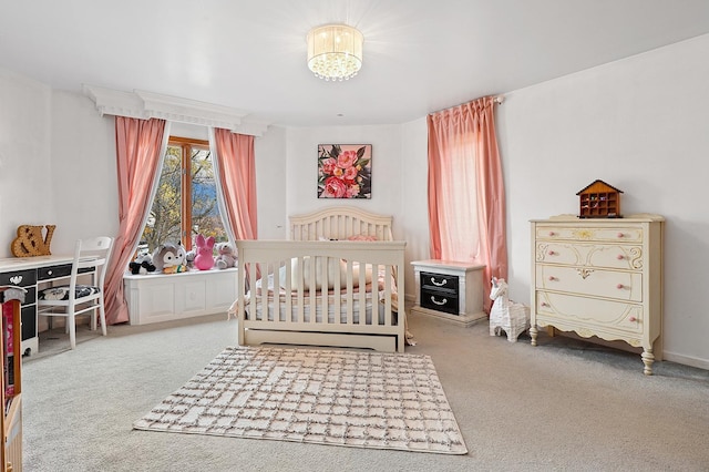 carpeted bedroom featuring a chandelier and a crib