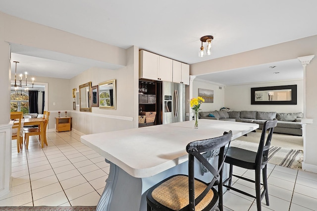 kitchen with stainless steel fridge, open floor plan, white cabinets, and light tile patterned floors