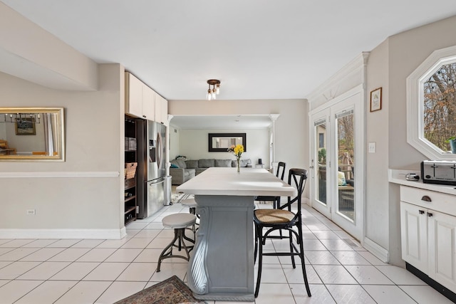 dining space featuring baseboards, french doors, and light tile patterned flooring