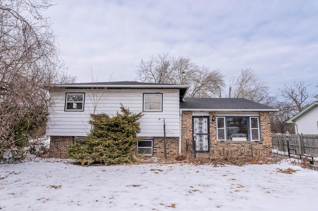 tri-level home with fence and brick siding