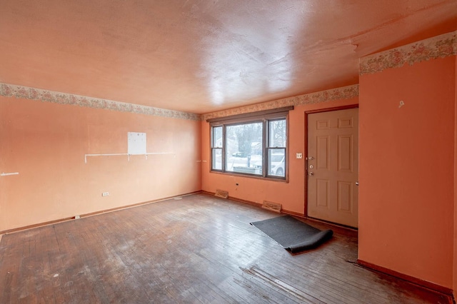 spare room with baseboards, visible vents, and wood finished floors