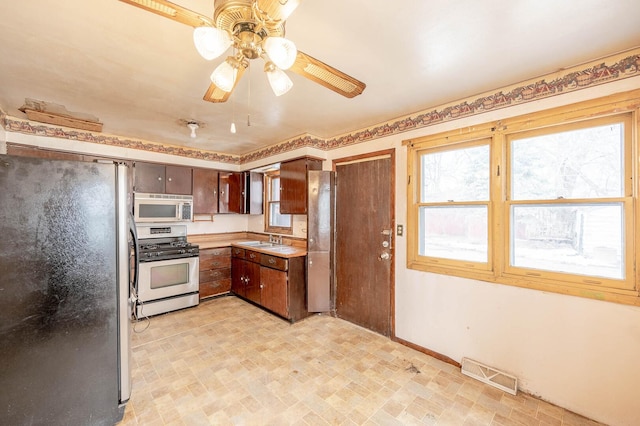 kitchen featuring ceiling fan, stainless steel appliances, a sink, visible vents, and light countertops